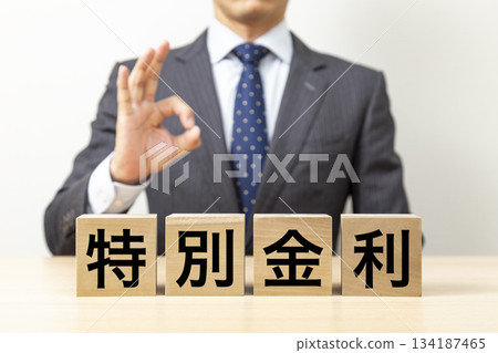 一位商人擺出「OK」的姿勢,旁邊立著一塊寫著「特惠利率」的牌子。 一位商人擺出「OK」的姿勢,旁邊立著一塊寫著「特惠利率」的牌子。 134187465