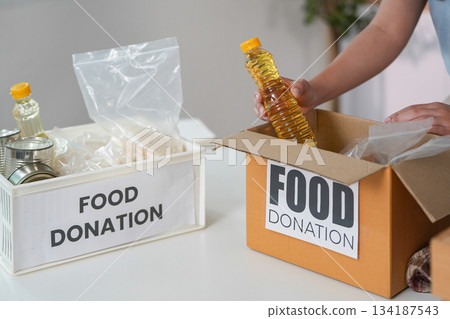 Food Donation. Individual placing cooking oil into donation box. 134187543