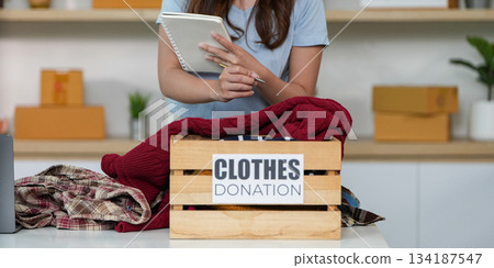 Clothes Donation. Young woman organizing items for charity. 134187547