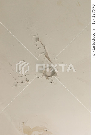 Ceiling of an old house displays noticeable cracks and peeling paint, indicating long-term neglect and deterioration. The surrounding environment feels neglected and abandoned 134187576