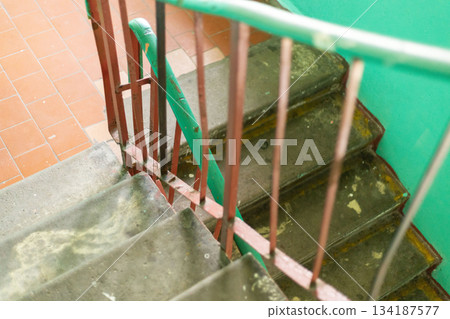 Staircase in an old house is worn and damaged. Peeling paint and dirt highlight years of neglect in this once vibrant home. The green walls add to the sense of abandonment Staircase in an old house is worn and damaged. Peeling paint and dirt highlight years of neglect in this once vibrant home. The green walls add to the sense of abandonment 134187577