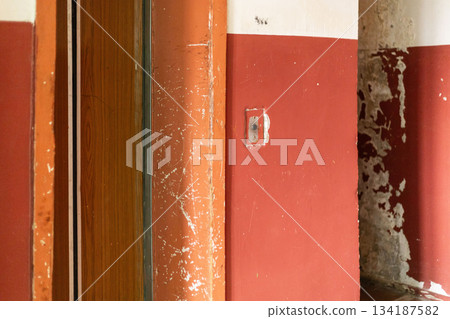 The interior of an old house reveals walls in deteriorating condition, marked by peeling paint and wear. The space conveys a sense of abandonment and age, highlighting the need for repairs 134187582
