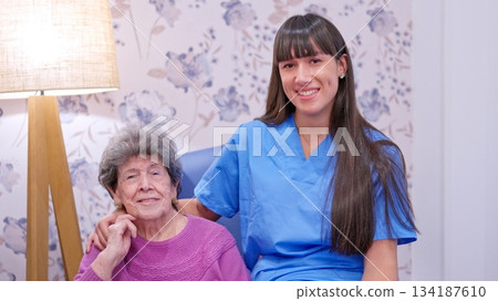 Caregiver supporting senior woman smiling at nursing home Caregiver supporting senior woman smiling at nursing home 134187610