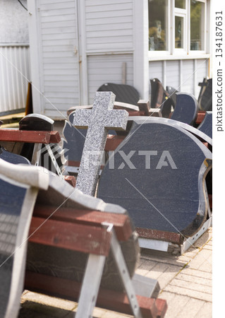 In a serene outdoor setting, a variety of tombstones are displayed for sale. Different shapes and sizes are stacked neatly, inviting visitors to browse for a suitable memorial 134187631