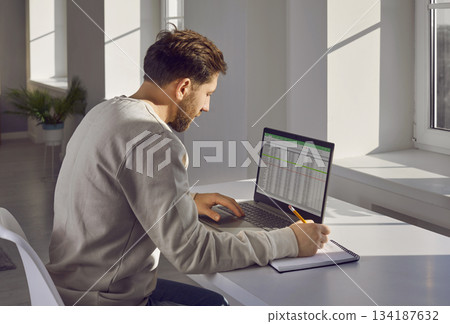 Side view shot of businessman working with spreadsheet in office Side view shot of businessman working with spreadsheet in office 134187632