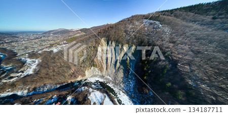 Drone photography of mountain slopes, rocks and hills with snow, trees and countryside villages. Yaremche, Carpathian mountains, Ukraine. Drone photography of mountain slopes, rocks and hills with snow, trees and countryside villages. Yaremche, Carpathian mountains, Ukraine. 134187711