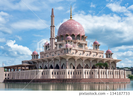 Putra Mosque, Putrajaya, Malaysia. Iconic pink dome and minaret architecture by the lake under a blue sky. 134187733