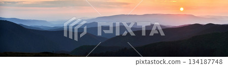 Panoramic view of tranquil scene at dusk, showcasing layers of rolling hills bathed in soft blue hues, with fading light of sunset casting gentle orange and pink glow over distant horizon. Panoramic view of tranquil scene at dusk, showcasing layers of rolling hills bathed in soft blue hues, with fading light of sunset casting gentle orange and pink glow over distant horizon. 134187748