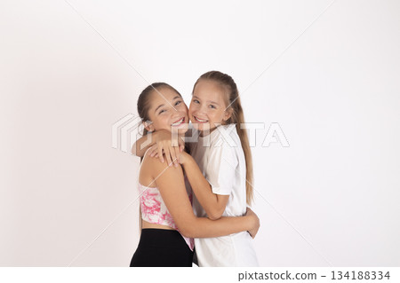 Two happy young women teenagers embracing and laughing together 134188334