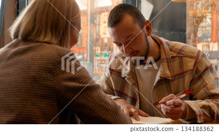 Focused man and woman collaborating on a project or educational material Focused man and woman collaborating on a project or educational material 134188362