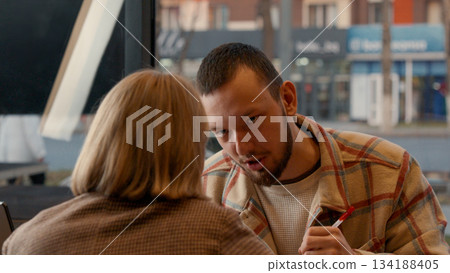Man and woman in conversation, looking at each other across a table 134188405