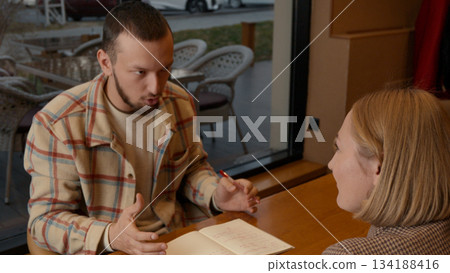 Man and woman having a serious discussion at a table in a modern setting Man and woman having a serious discussion at a table in a modern setting 134188416