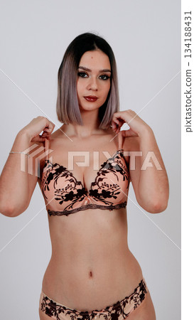 Sensual woman in floral lace bra, hands covering chest, shy expression 134188431