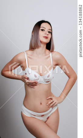 Woman in white lace lingerie with hands on her hip, posing confidently 134188862