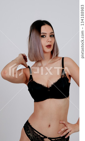 Seductive woman in black lace lingerie posing against white background Seductive woman in black lace lingerie posing against white background 134188983