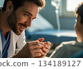 Caring male doctor holding a patient hand and smiling reassuringly in a hospital room. 134189127