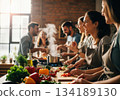 Joyful group of young adults cooking and chopping fresh vegetables in a modern kitchen 134189130