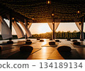 Serene outdoor yoga pavilion at sunset decorated with fairy lights and meditation cushions 134189134