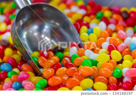 Glazed beaded candies on a store counter with a scoop dipped in. Many colorful candies in soft focus. Delicious background. Glazed beaded candies on a store counter with a scoop dipped in. Many colorful candies in soft focus. Delicious background. 134189197