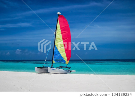 Sailing boat with colorful sail on sandy beach near the ocean bay. Sailing boat with colorful sail on sandy beach near the ocean bay. 134189224