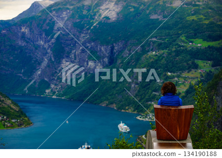 Tourist enjoying fjord Geiranger from viewpoint Tourist enjoying fjord Geiranger from viewpoint 134190188