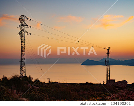 High voltage towers on coast at sunset High voltage towers on coast at sunset 134190201