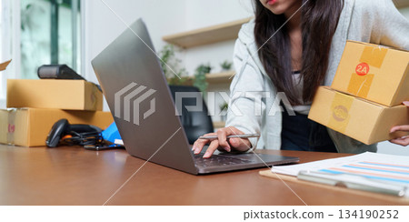 E-commerce Operations: Woman Managing Packages on Laptop E-commerce Operations: Woman Managing Packages on Laptop 134190252