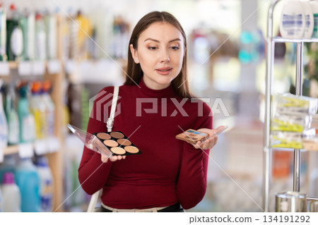 Young woman choosing a palette with eyeshadow and powder Young woman choosing a palette with eyeshadow and powder 134191292