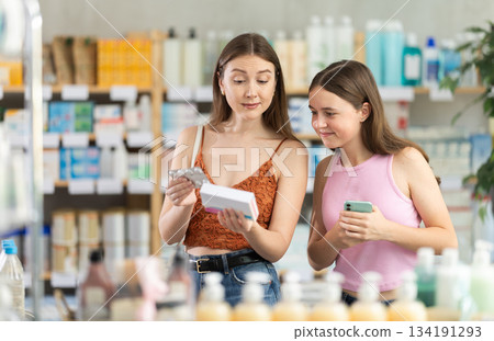 Daughter with her mother in summer dress choose pills in pharmacy Daughter with her mother in summer dress choose pills in pharmacy 134191293