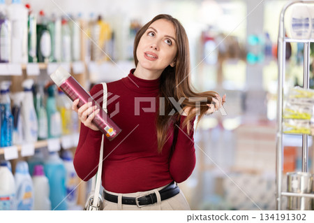 Young woman choosing hairspray in store Young woman choosing hairspray in store 134191302