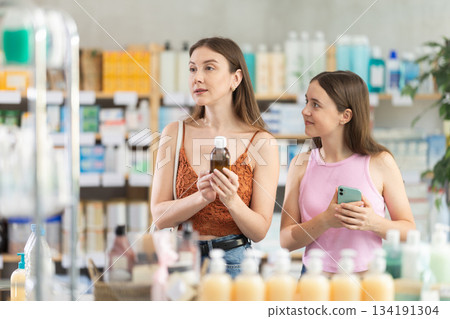 Woman with daughter choosing syrup in pharmacy 134191304
