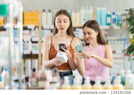 Woman and teen girl in pharmacy scans QR code cream product Woman and teen girl in pharmacy scans QR code cream product 134191308