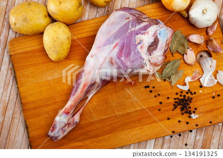 Raw lamb leg with potatoes and condiments Raw lamb leg with potatoes and condiments 134191325