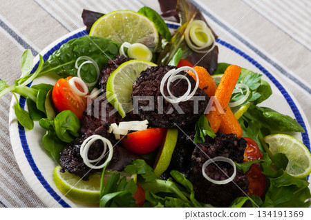 Fried tasty blood sausage with lettuce and lemon, served at plate 134191369