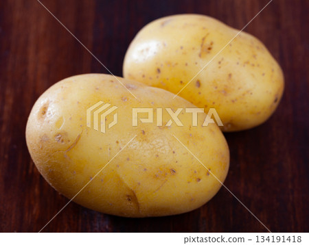 Closeup many potato tubers on wooden surface Closeup many potato tubers on wooden surface 134191418