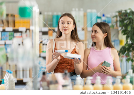 Woman with daughter choosing ointment in pharmacy 134191466