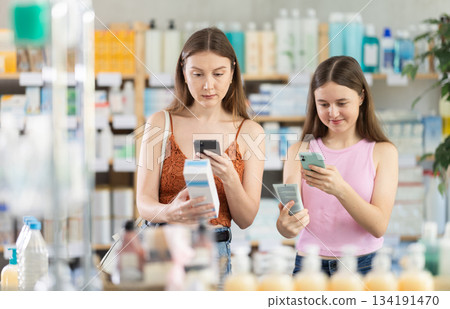 European woman and her daughter scan the barcode of a cream European woman and her daughter scan the barcode of a cream 134191470