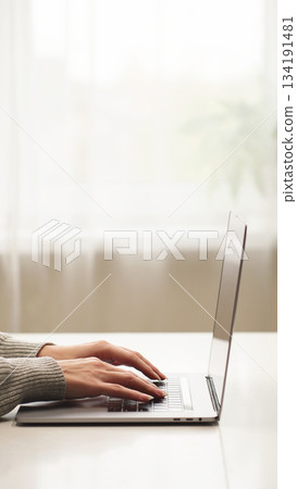 Close-up woman's hands typing on a laptop at home, working on email, business report, data entry, research, and remote communication for company tasks. 134191481