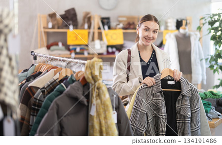 Adult woman chooses coat in clothing store Adult woman chooses coat in clothing store 134191486