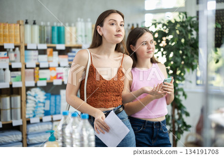 In drugstore, mom and daughter with prescription looking for something 134191708