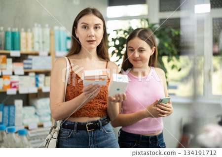 Woman with daughter choosing pills in pharmacy 134191712