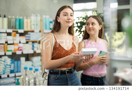 Woman with daughter choosing pills in pharmacy Woman with daughter choosing pills in pharmacy 134191714