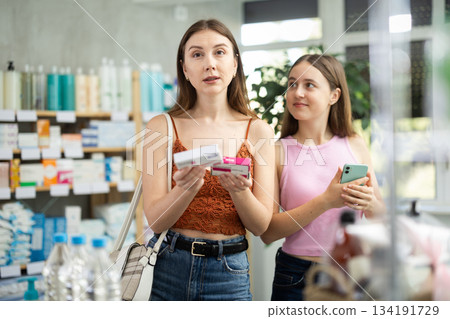 European woman with daughter standing in pharmacy with ointment European woman with daughter standing in pharmacy with ointment 134191729