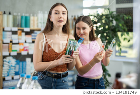 Woman with girl child buyer select toothbrush set Woman with girl child buyer select toothbrush set 134191749