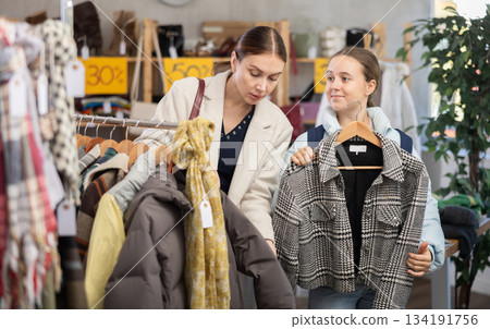 Teen girl with mother choosing something for autumn-winter in clothing store Teen girl with mother choosing something for autumn-winter in clothing store 134191756