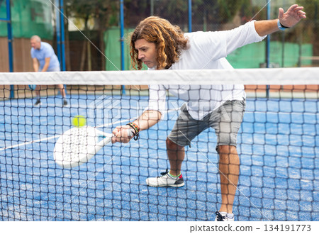 Caucasian man playing paddle tennis on padel court 134191773