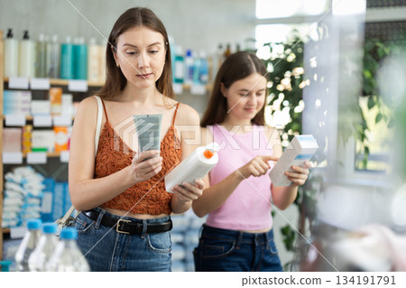 Mother and daughter choose a cream at the pharmacy 134191791
