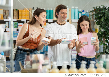 Father, mother and daughter choose pills together at drugstore Father, mother and daughter choose pills together at drugstore 134191792