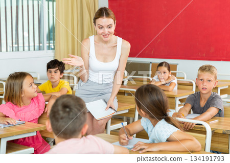 Friendly female teacher working with preteen pupils in class Friendly female teacher working with preteen pupils in class 134191793