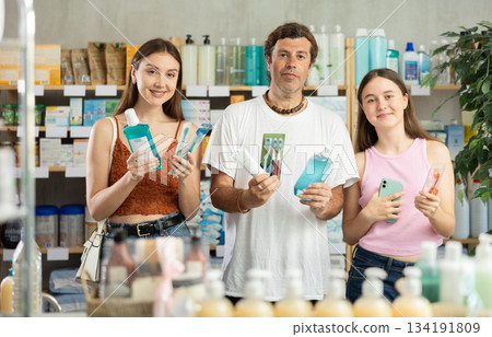 Father, mother and daughter choose toothbrushes together at drugstore Father, mother and daughter choose toothbrushes together at drugstore 134191809